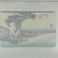 estampe japonaise de paysage d'Hiroshige, un homme et une femme attise le feu sous une bouilloire accrochée à un arbre au milieu des champs de riz, le texte sur papier cristal