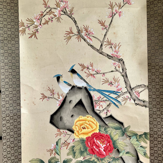 rouleau suspendu kakejiku un couple d'oiseaux bleu et blanc sur un rocher. Des pivoines jaune et rouge au pied du rocher, une branche de cerisier en fleurs à l'arrière