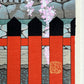 estampe japonaise cerisier en fleur descendant sur une barrière rouge et noire, gros plan sur la barrière et sceau de l'artiste