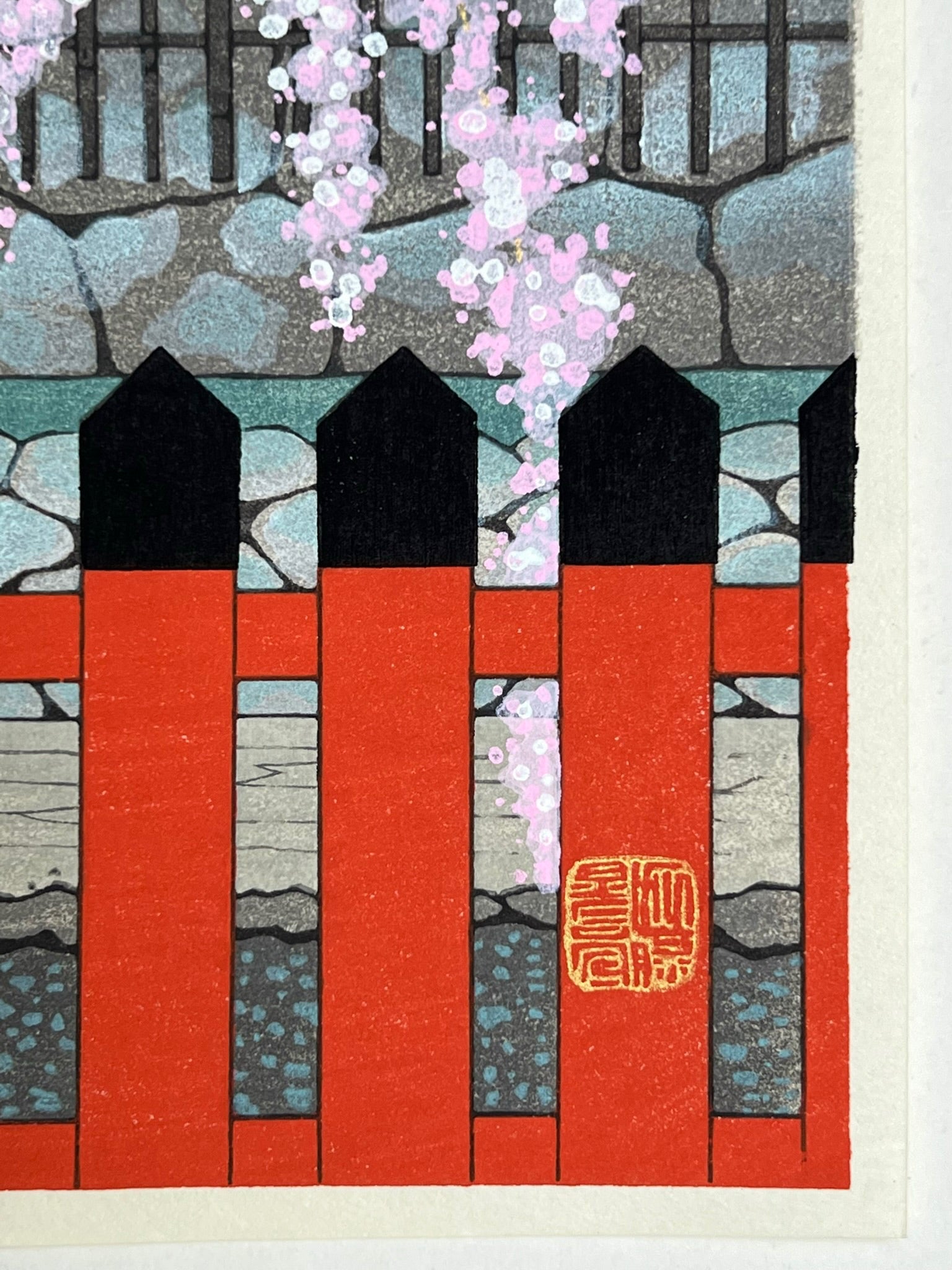 estampe japonaise cerisier en fleur descendant sur une barrière rouge et noire, gros plan sur la barrière et sceau de l'artiste