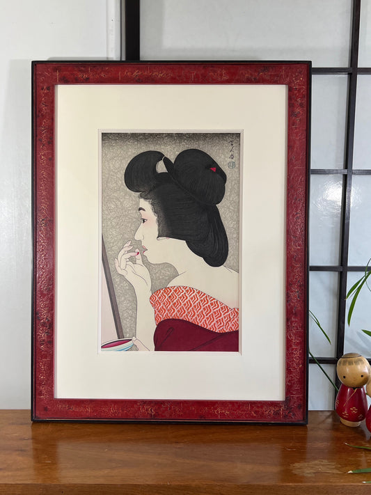 estampe japonaise portrait de femme se maquillant avec du rouge à lèvres style Shin-Hanga de Kotondo, avec cadre Lys de Provence, façon cuir rouge vieilli.