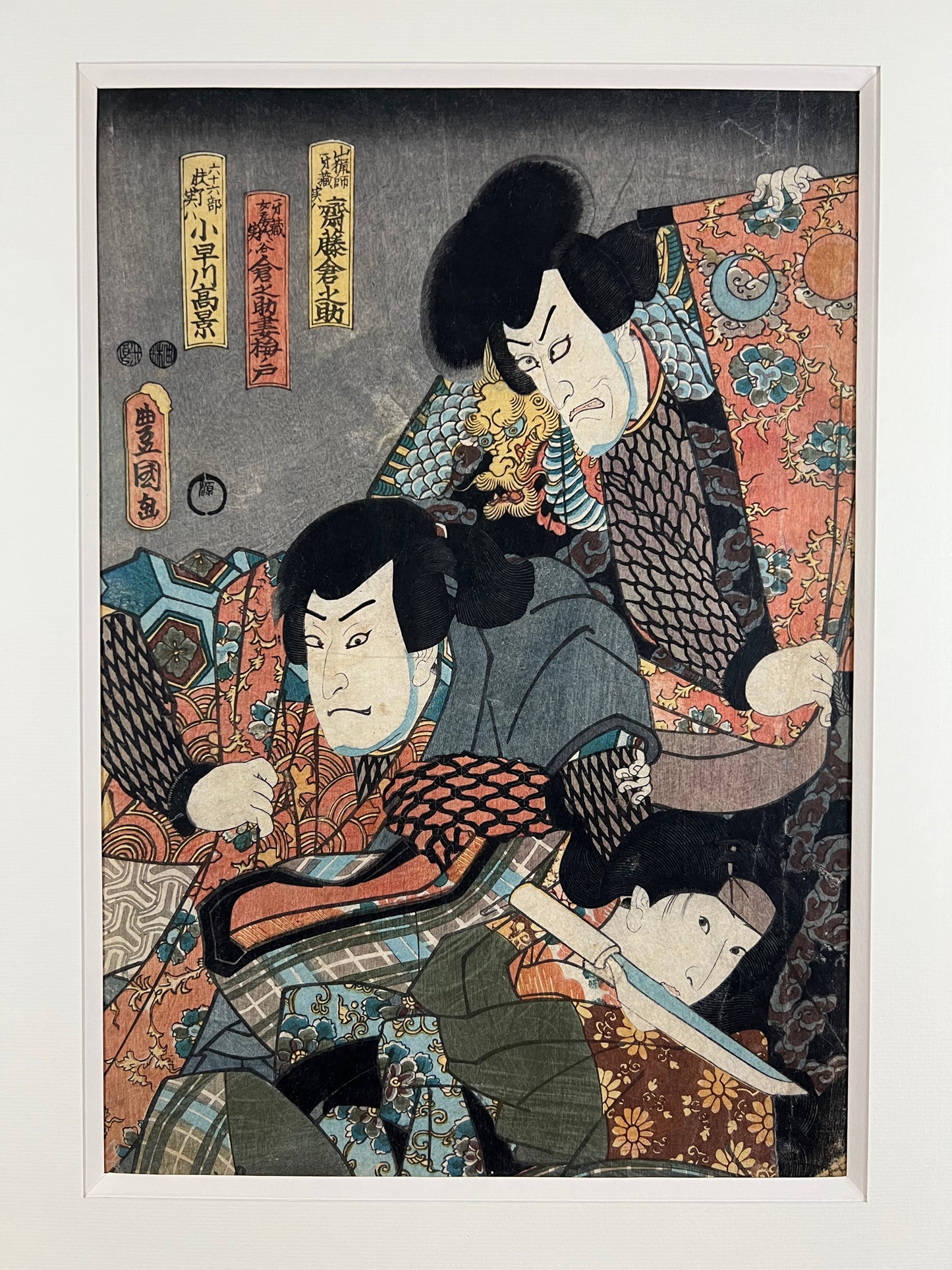 estampe japonaise originale de Kunisada représentant deus samouraïs et une femme dans une pièce de théâtre kabuki