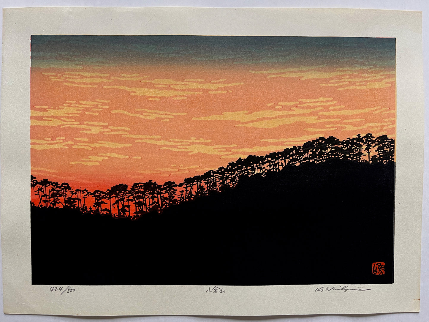 estampe japonaise contemporaine, les arbres du sommet de la montagne se découpent en ombre chinoise sur la lumière rouge flamboyante du coucher de soleil
