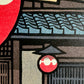 estampe japonaise grosse lanterne rouge avec calligraphie noire devant l'entrée en bois et tuiles bleu vernies d'un restaurant traditionnel, gros plan sur la petite lanterne et les tuiles vernissées