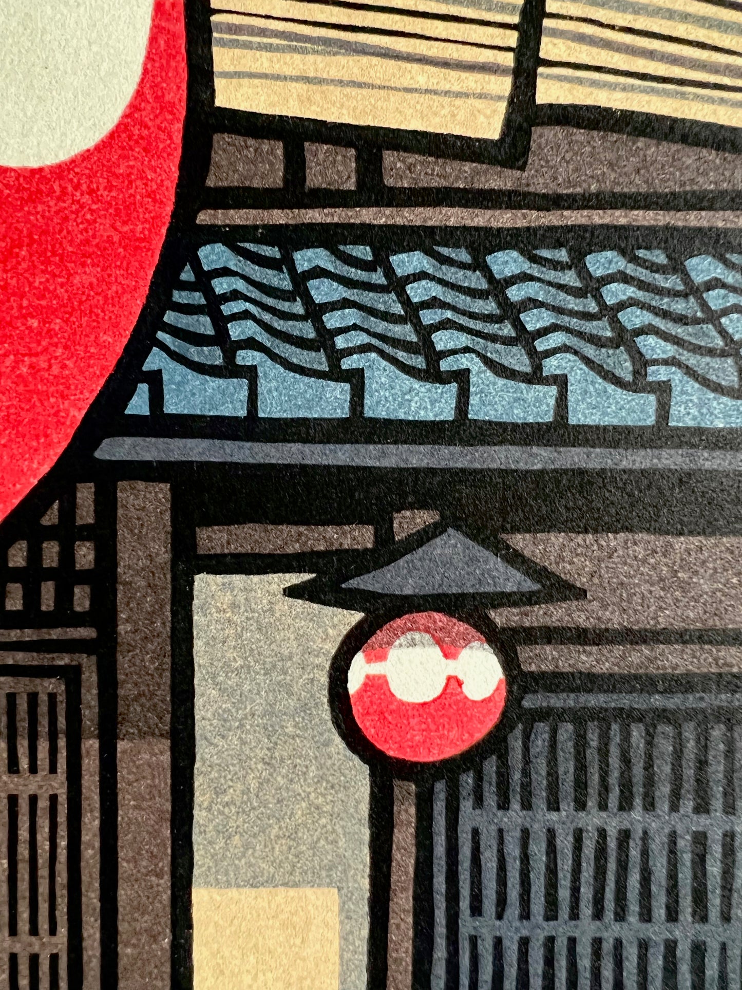 estampe japonaise grosse lanterne rouge avec calligraphie noire devant l'entrée en bois et tuiles bleu vernies d'un restaurant traditionnel, gros plan sur la petite lanterne et les tuiles vernissées