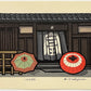 estampe japonaise contemporaine de Nishijima,deux parapluies bicolores séchant au soleil devant entree de maison avec un noren,  chez Uchiwa Gallery