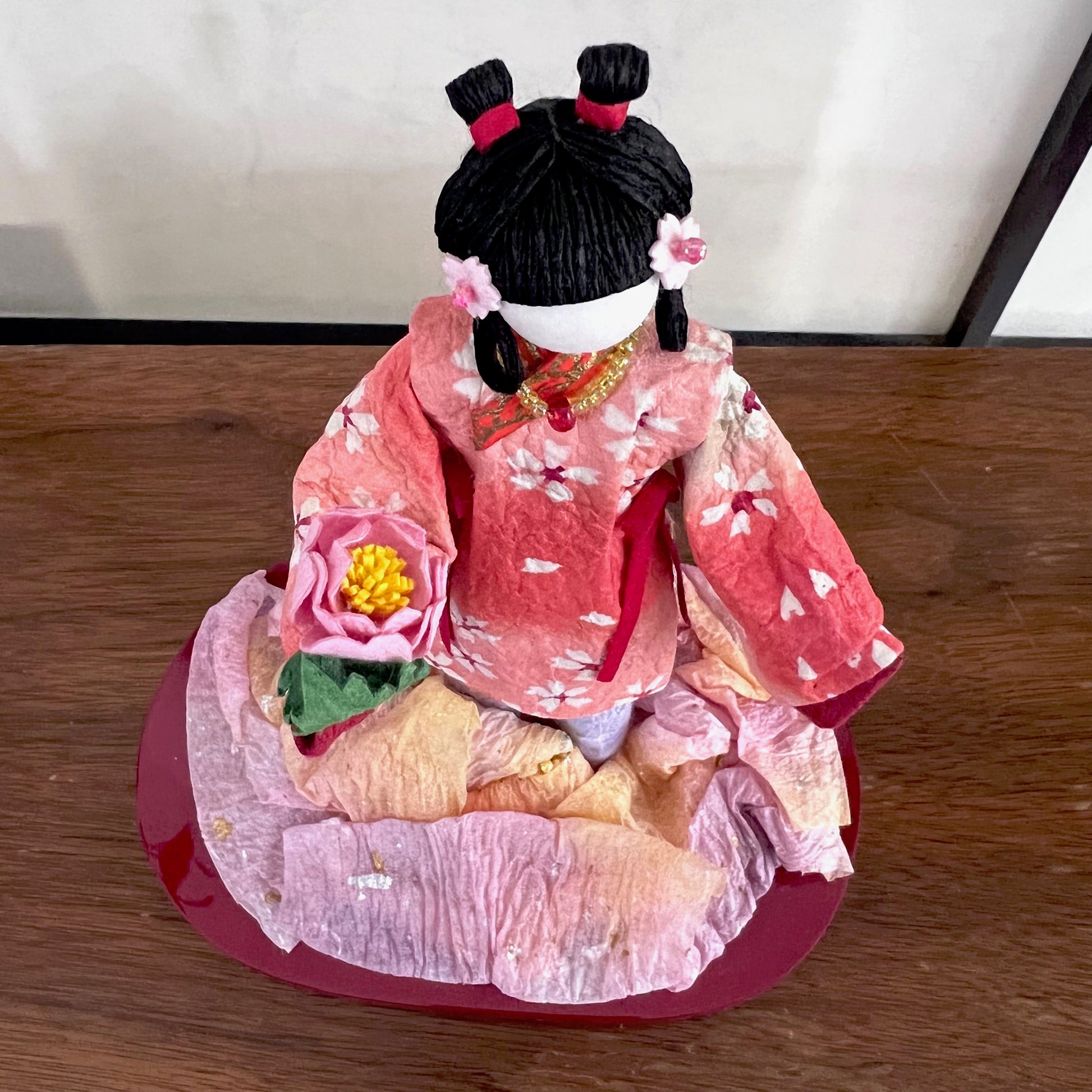 poupée japonaise en papier Yuzen Washi, ( Washi Doll)au kimono fleurs de cerisier tenant une pivoine rose dans la main, vu de dessus