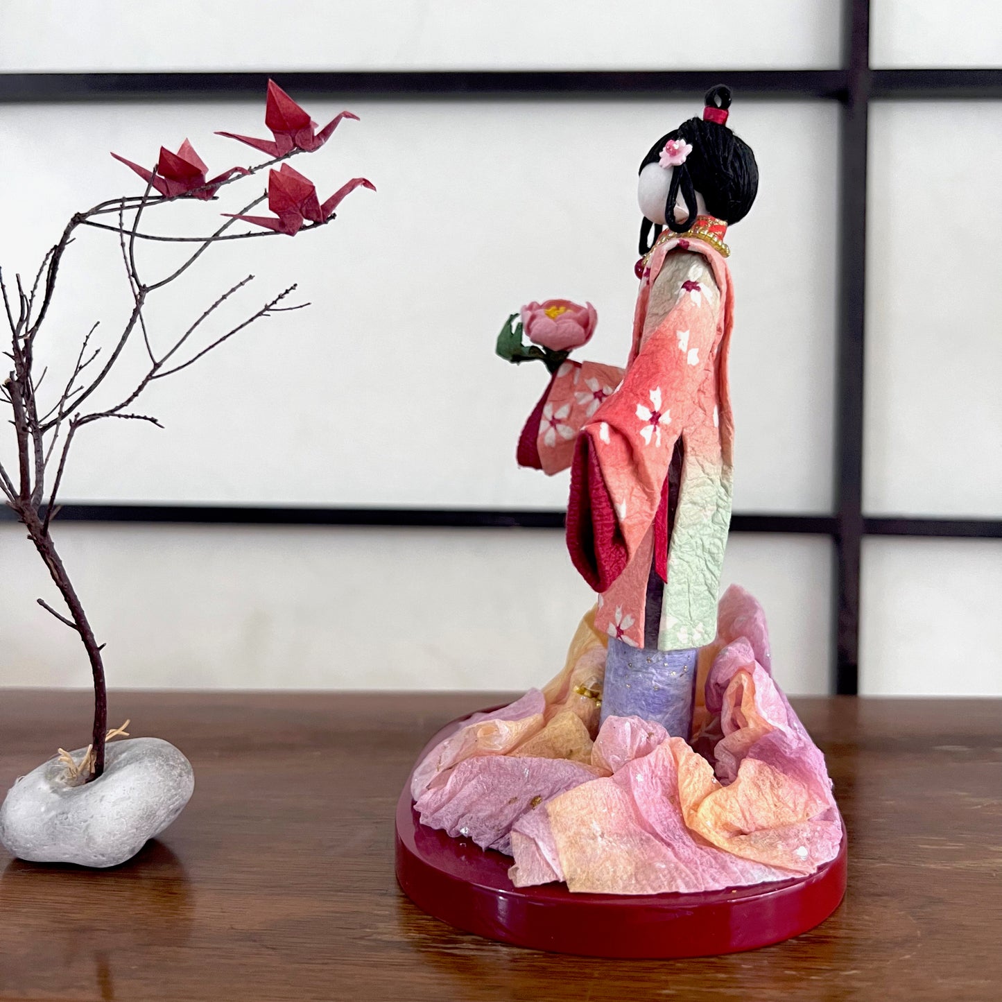 poupée japonaise en papier Yuzen Washi, ( Washi Doll)au kimono fleurs de cerisier tenant une pivoine rose dans la main, vu du côté gauche