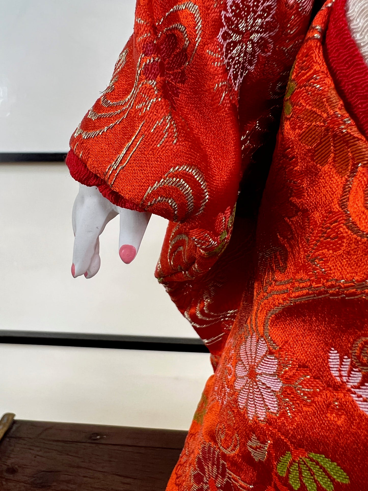 poupée japonaise Ichimatsu fille, le devant du kimono en soie rouge, détail de la main gauche en céramique, et vernis rose sur les ongles