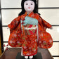 poupée japonaise Ichimatsu fille, le devant du kimono en soie rouge, vu de face manches dépliées