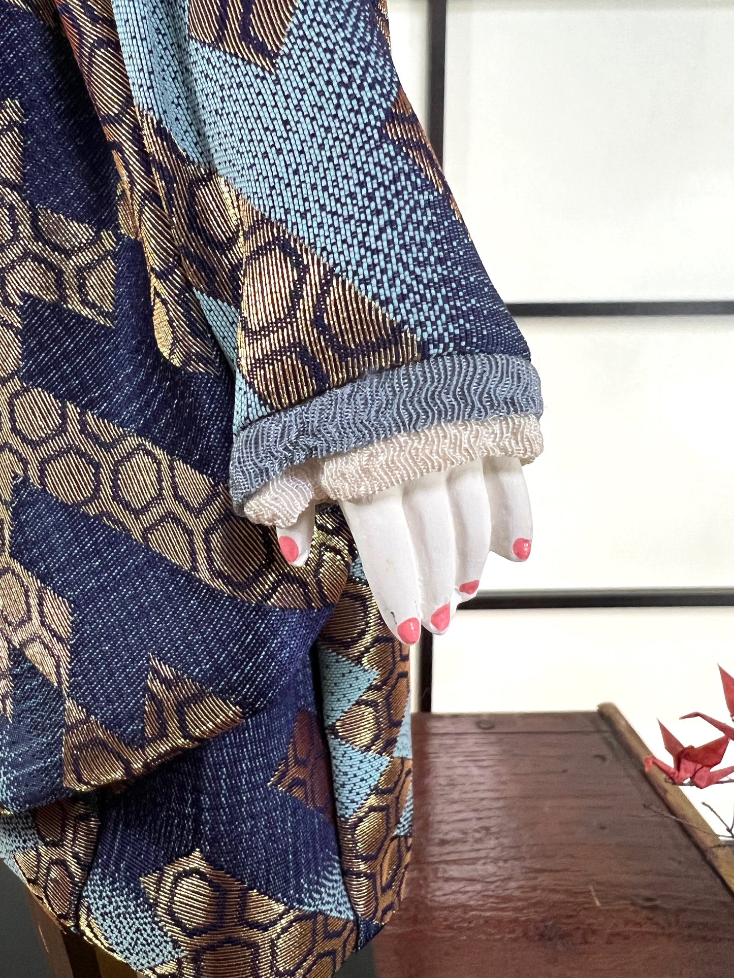 poupée japonaise Ichimatsu garçon, en kimono en soie bleu et beige, détail de la main gauche